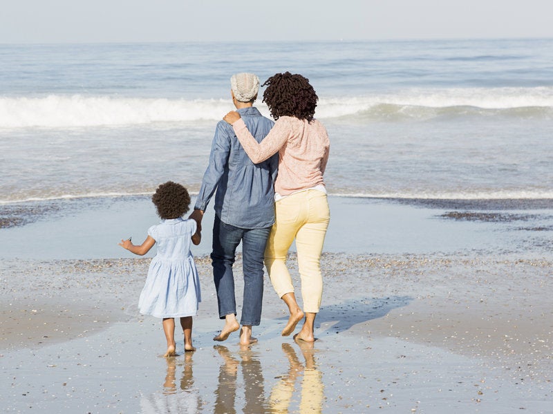 photo of a mother, daughter and grandchild, 3 generations, walking hand-in-hand along an ocean beach
